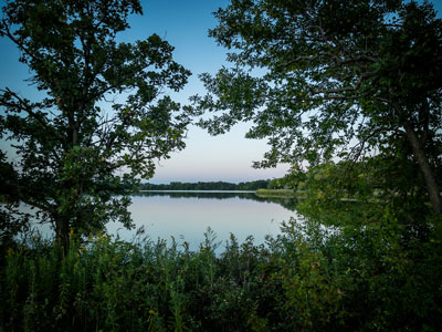Photo of a lake in the evening framed by trees